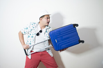 Young creative man is posing with suitcase on white background.
Holiday traveler concept