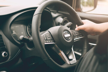 Fototapeta na wymiar Closeup male hand driving a car with interior luxury dashboard and steering wheel.