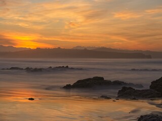Fototapeta na wymiar Golden reflection of the sunset on Liencres beach