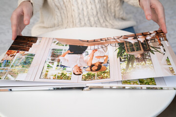 close up. a woman flips through a photo book from a family pregnancy photo shoot. beautiful and...