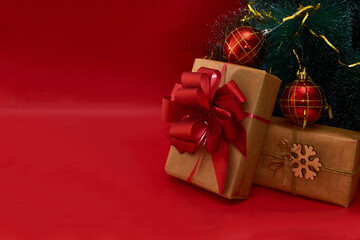 New Year or Christmas presents under a decorated Christmas tree on a red background with copy space