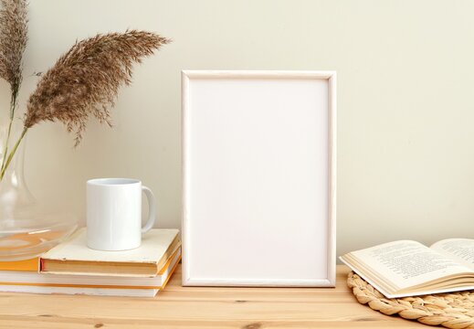 Blank frame mockup and boho style decorations, books and coffee cup, empty white frame for print, photo, artwork, lettering, design.