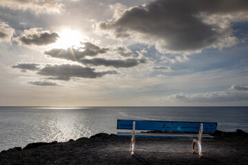 Fototapeta na wymiar blue wooden bench to relax and watch the sunset in Fuerteventura, Spain
