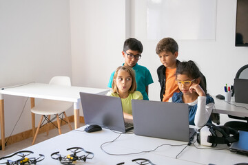 Little classmates doing group task, using laptops and studying at computer school. Concentrated...