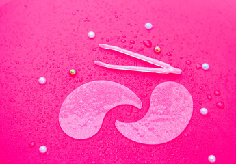 Hydrogel cosmetic moisturizing collagen eye patches on pink background with water drops