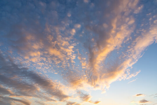 A sky with cloud streets that are lit from below after sunset