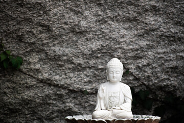 Small Buddhist statue against a stone background. 