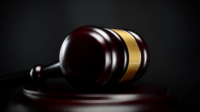 Gavel being struck to decide an auction or guilty verdict in court. Black background.