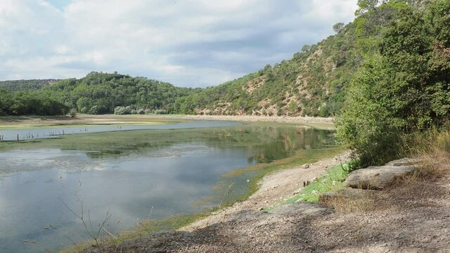 Video of The lake of Sainte Suzanne called lac de Carc&egrave;s along forestry path with view on low water level when the dam is drained or pumped water in dry period