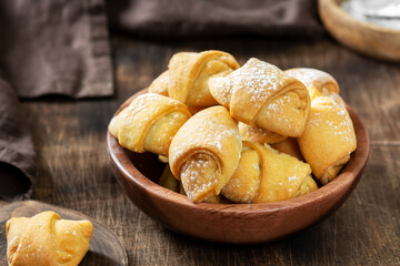 Lots of bagels. Puff pastry in a wooden plate on a brown table. Cookies close up	