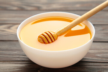 Bowl of honey on brown wooden table. Top view.