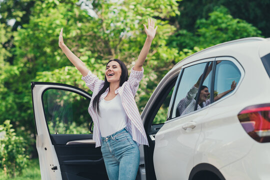 Photo of positive cheerful girl drive ride car park forest trees stop raise arms enjoy summer fresh air wind blow city town outdoors escape concept
