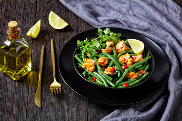 Curried salmon with green beans on a black plate