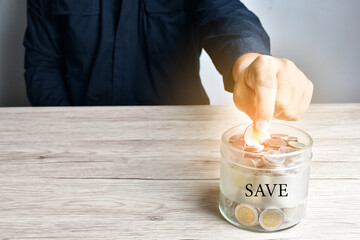 A businessman put a coin in a glass jar or battle  as a savings in the bank when it was full.