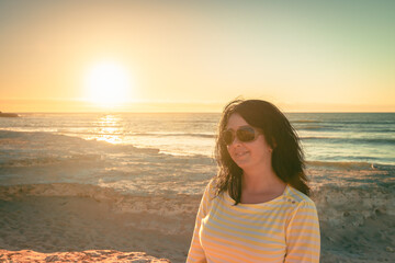 Woman sitting on beach and enjoying sunset at Port Noarlunga, South Australia