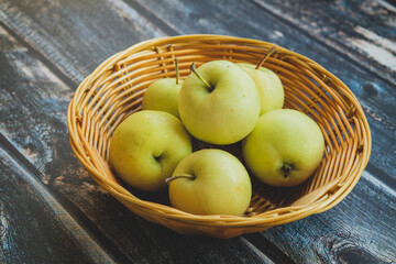 green apples in a basket on a light wooden background