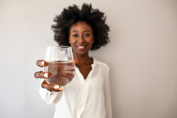 African-American Woman holding glass of water. Happy beautiful young woman holding drinking water...