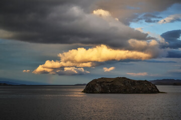 evening bright yellow orange sunset with clouds on lake baikal with island and mountains