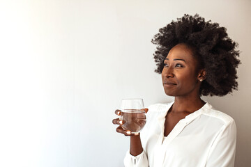 Close up focus on female hand holding glass african woman drinking still water having thirst...