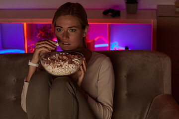 Young woman with popcorn scare during watching movie at home
