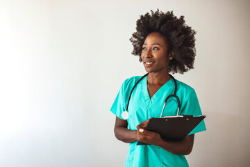 Studio shot of an attractive young nurse using a clipboard against a grey background. Portrait Of...