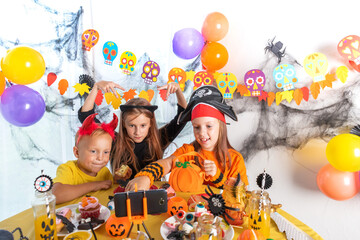 Dressed in spooky halloween costumes kids headwear having video chat on laptop with friends in decorated home.