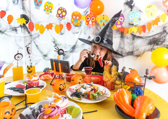 Dressed in spooky halloween costumes girl headwear having video chat on laptop with friends in...