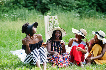 Group of african american girls celebrating birthday party and eat muffins outdoor with decor.