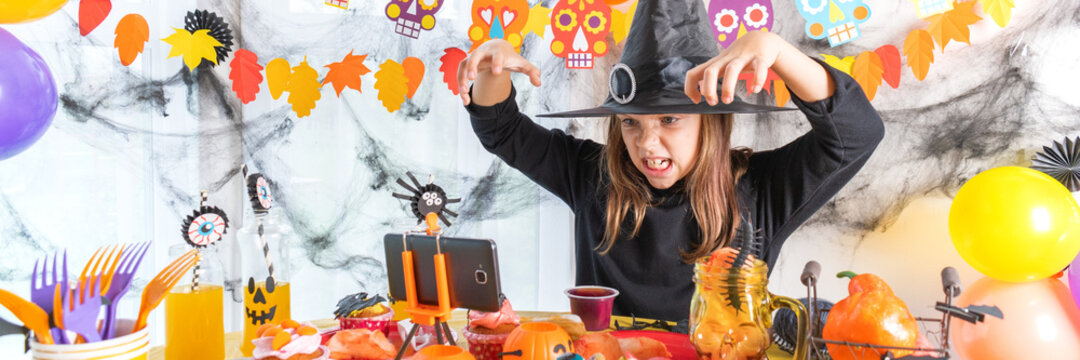 Dressed In Spooky Halloween Costumes Girl Headwear Having Video Chat On Laptop With Friends In Decorated Home. Banner