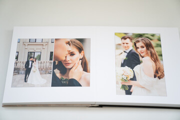 open wedding photo book. flipping through a photobook with thick pages on a white table....