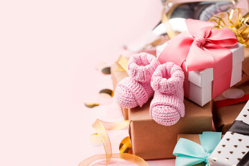Pair of small pink baby socks and gift box on pink background with gift present boxes and copy...