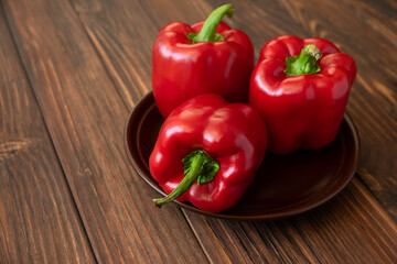 Red bell peppers on brown wooden table. Selective focus. Copy space