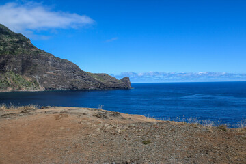 Grandes montañas de rocas y arboles y pasto verde en las costas del mar con un cielo azul con...