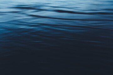 Close-up of water texture, smooth blue waves of water on the shore beach, color landscape photo of water 