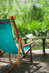 Wooden beach chair in the garden and some books on the table. Relaxing place concept.