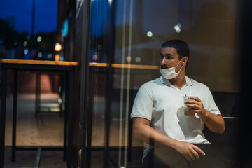 Joven mirando a través del cristal desde interior de cafetería