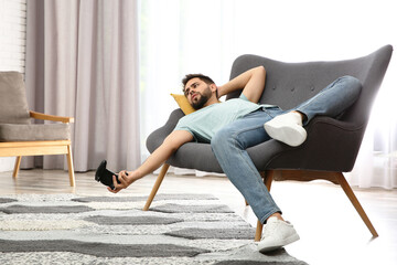 Lazy young man playing video game while lying on sofa at home