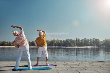 Two senior people stretching her oblique muscles