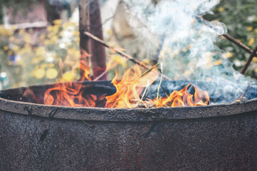 Flame of fire and smoke from an old rusty barrel. Selective focus on the barrel