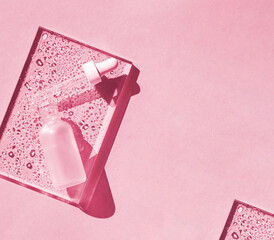Cosmetic hydrating serum in a glass bottle with pipette. Hyaluronic acid on the pink background top...