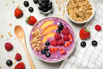 Delicious acai smoothie in bowl and ingredients on light grey table, flat lay