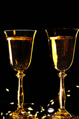 Christmas background concept. Two glasses with champagne and garland lights on a black background.