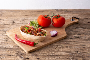 Mexican barquita taco with beef, chilli, tomato, onion and spices on wooden table