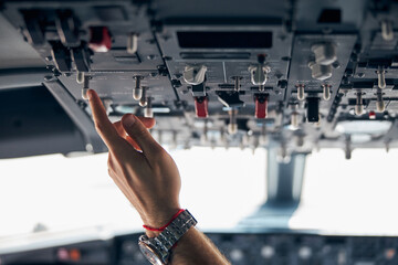Pilot on plane and crew touching equipment on dashboard