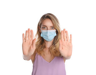 Woman in protective face mask showing stop gesture on white background. Prevent spreading of coronavirus