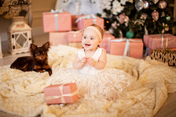 Cute baby girl smiles among new year's gifts in the Christmas interior. New year's gift concept. new year 2021