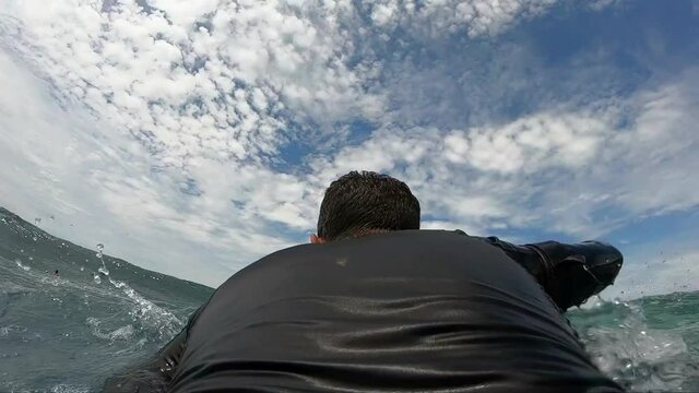 Slow motion shot of a bodyboarder surfer duck dives under a wave out in the surf