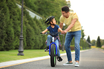 Dad teaching son to ride bicycle outdoors