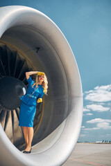 Charming flight attendant standing on plane engine