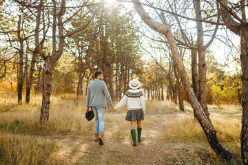 Stylish and loving couple enjoying each other on a sunny day in the park. Hipster couple wearing beautiful hats and sweaters. The concept of youth, love, autumn and lifestyle.
